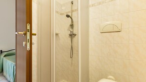 A bathroom with a shower, toilet, and a door with a lock.