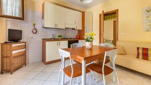 A compact kitchen with white cabinets, a wooden dining table, and a sofa.