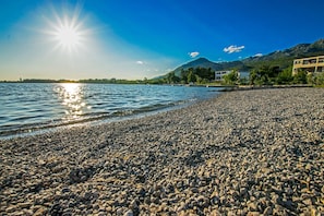 A pebbled beach with a mountain in the background and a clear sky.