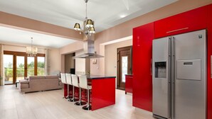 A modern kitchen with a red island, stainless steel appliances, and a large refrigerator.
