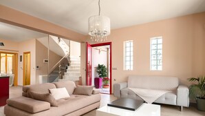 A spacious living room with a modern sofa, a coffee table, and a staircase leading to an upper floor.