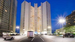 Um hotel com vários andares, átrio central, estacionamento e edifícios adjacentes.