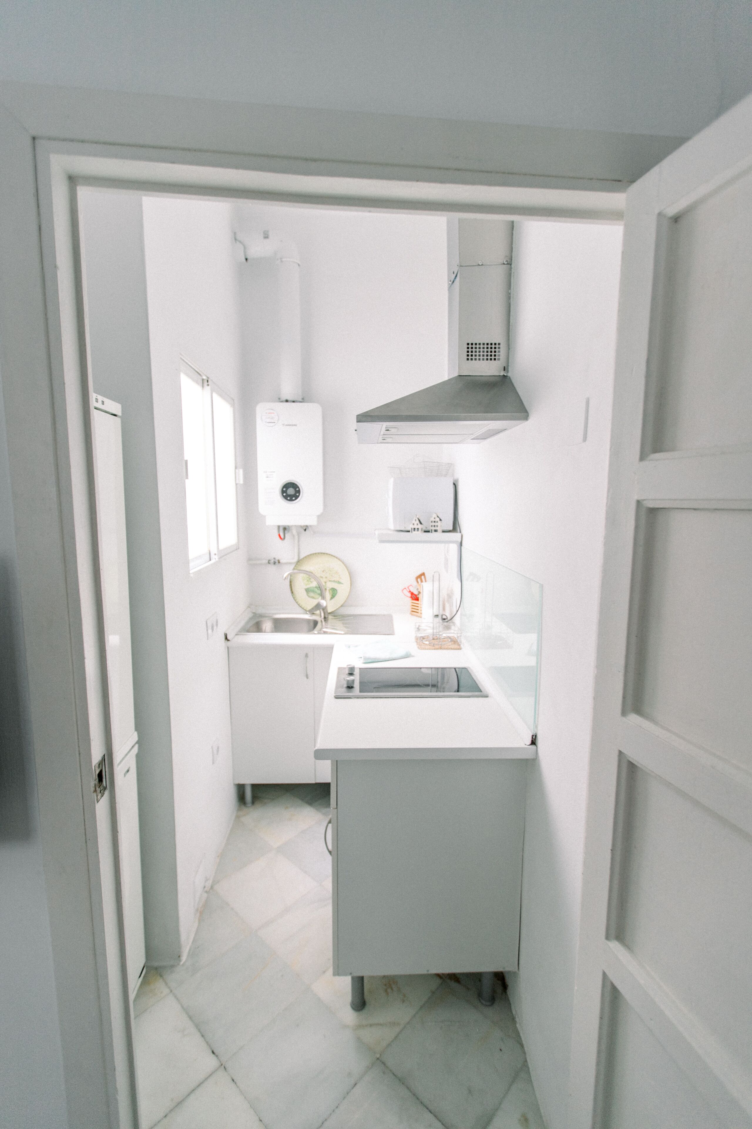 Una cocina compacta con lavavajillas integrado, un lavamanos y una estufa.