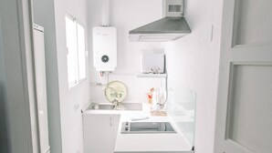 Una cocina compacta con lavavajillas integrado, un lavamanos y una estufa.