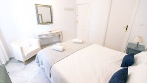 Una habitación de hotel con una cama, una silla, un escritorio y una puerta.