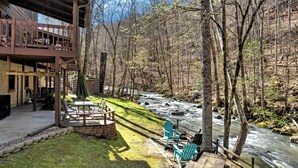 A cabin with a deck overlooking a river, surrounded by trees. - Stream On  -  River Front, $560 FREE tickets each paid day (Sevierville)