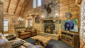 A log cabin interior with a stone fireplace, leather furniture, and a mounted moose head. - Stream On  -  River Front, $560 FREE tickets each paid day (Sevierville)