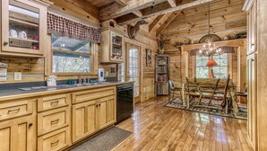 A wooden cabin interior with a kitchen featuring wooden cabinets, a sink, and a dining area with a bench. - Stream On  -  River Front, $560 FREE tickets each paid day (Sevierville)