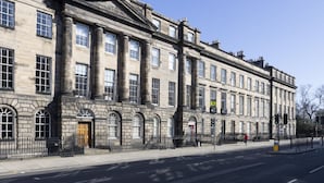 A historic building with large windows, a central entrance, and a symmetrical facade.