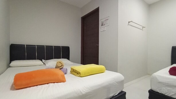 A hotel room with a bed, a nightstand, a wooden door, and a white wall. - OYO HOME 90261 Hom2rex Kuching Homestay (Kuching)