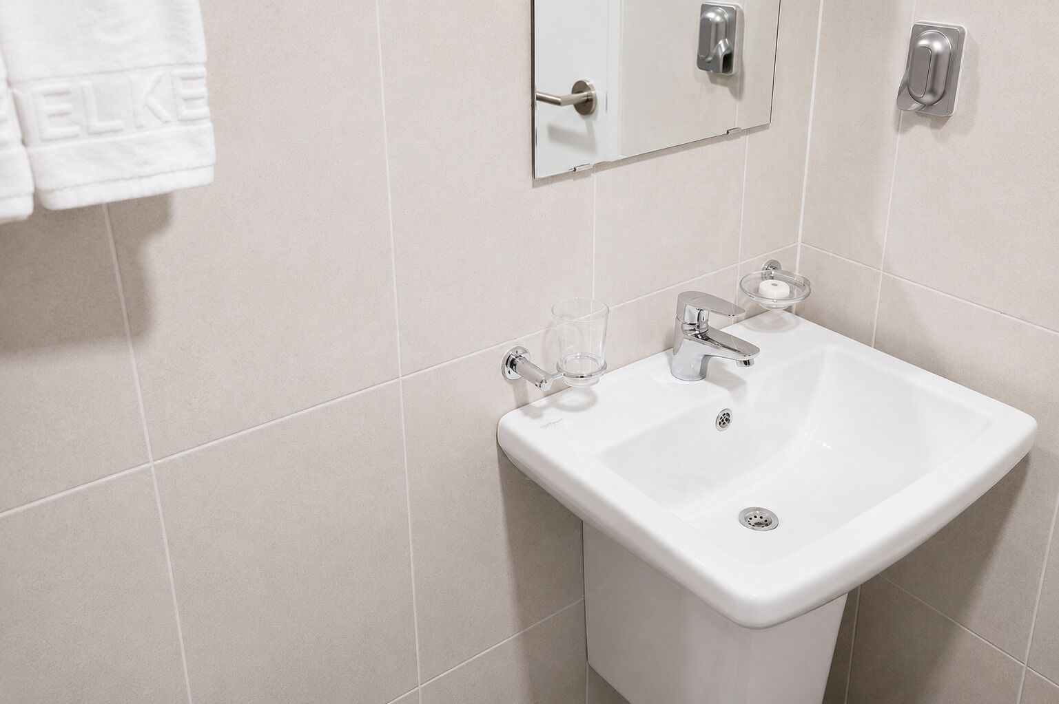 A white bathroom with a sink, mirror, and towel rack.