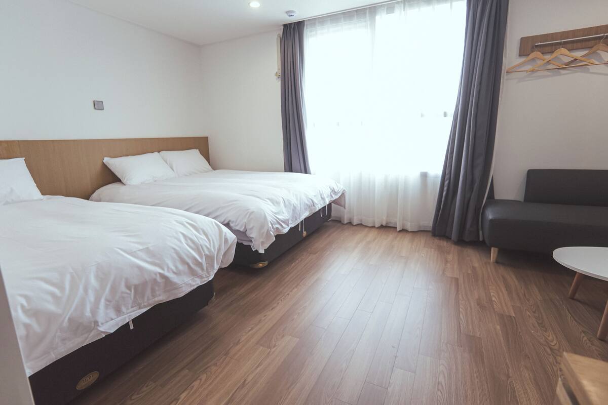 Ett hotellrum med två sängar, en soffa och ett litet bord.