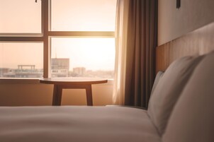 Una habitación de hotel con cama, una mesita y una ventana con cortinas.