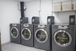 A row of four front-loading washing machines in a commercial setting. - Kenny Stay Jeju Mosulpo - Hotel Kenny (Seogwipo)