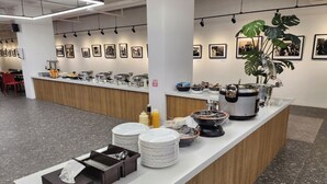 A buffet setup with plates, bowls, and condiments.