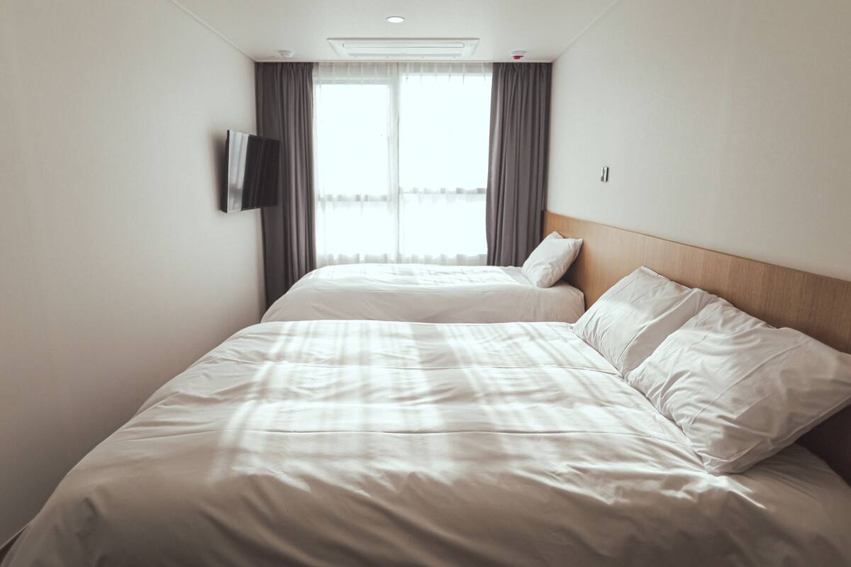 Ett hotellrum med en stor säng, en platt-TV som är monterad på väggen och ett fönster med gardiner.