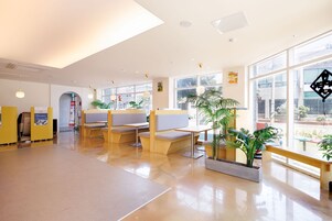 Un vestíbulo amplio con zonas de estar, ventanas grandes y plantas de interior.