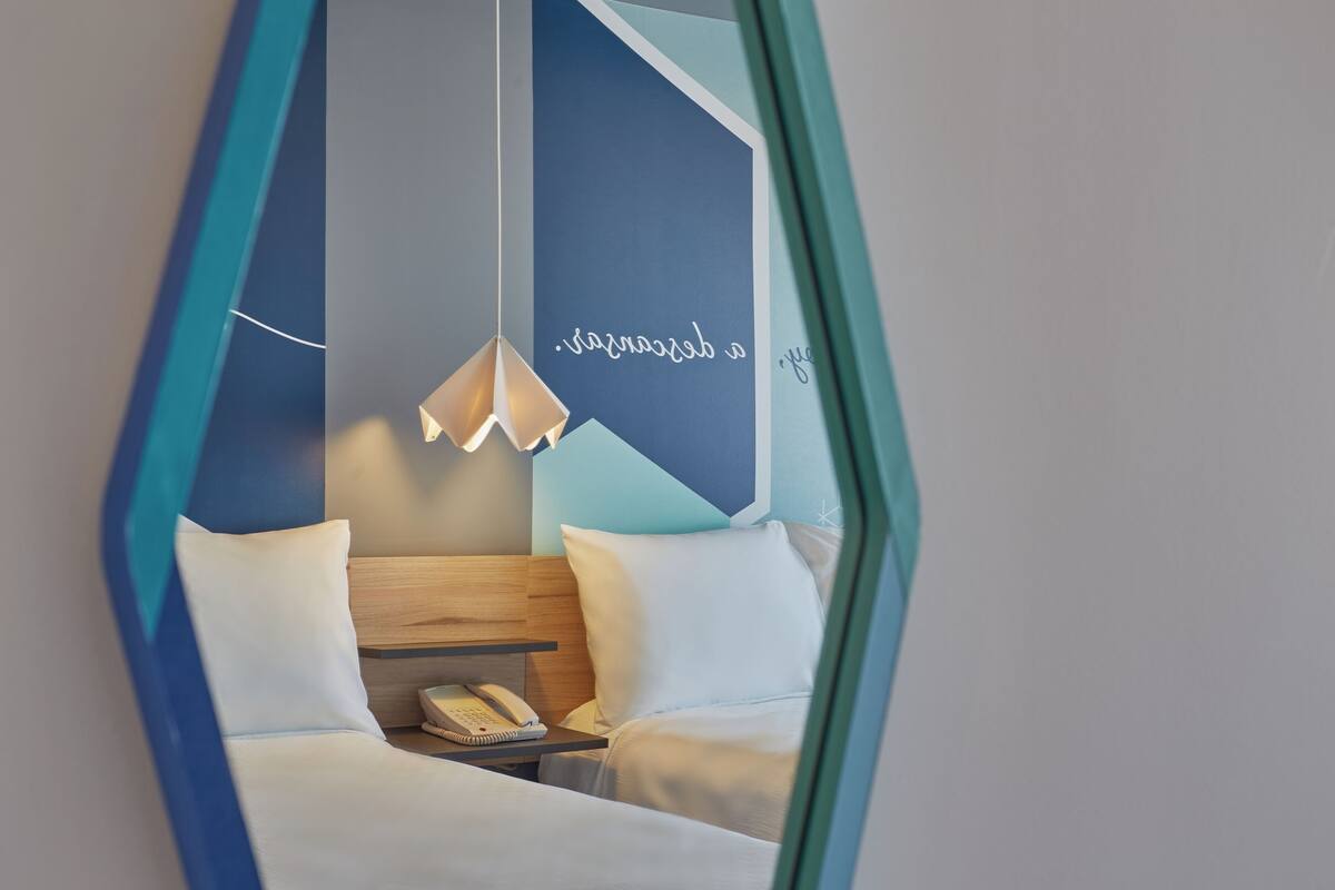 Une chambre d’hôtel avec un lit, une table de chevet et un luminaire suspendu.