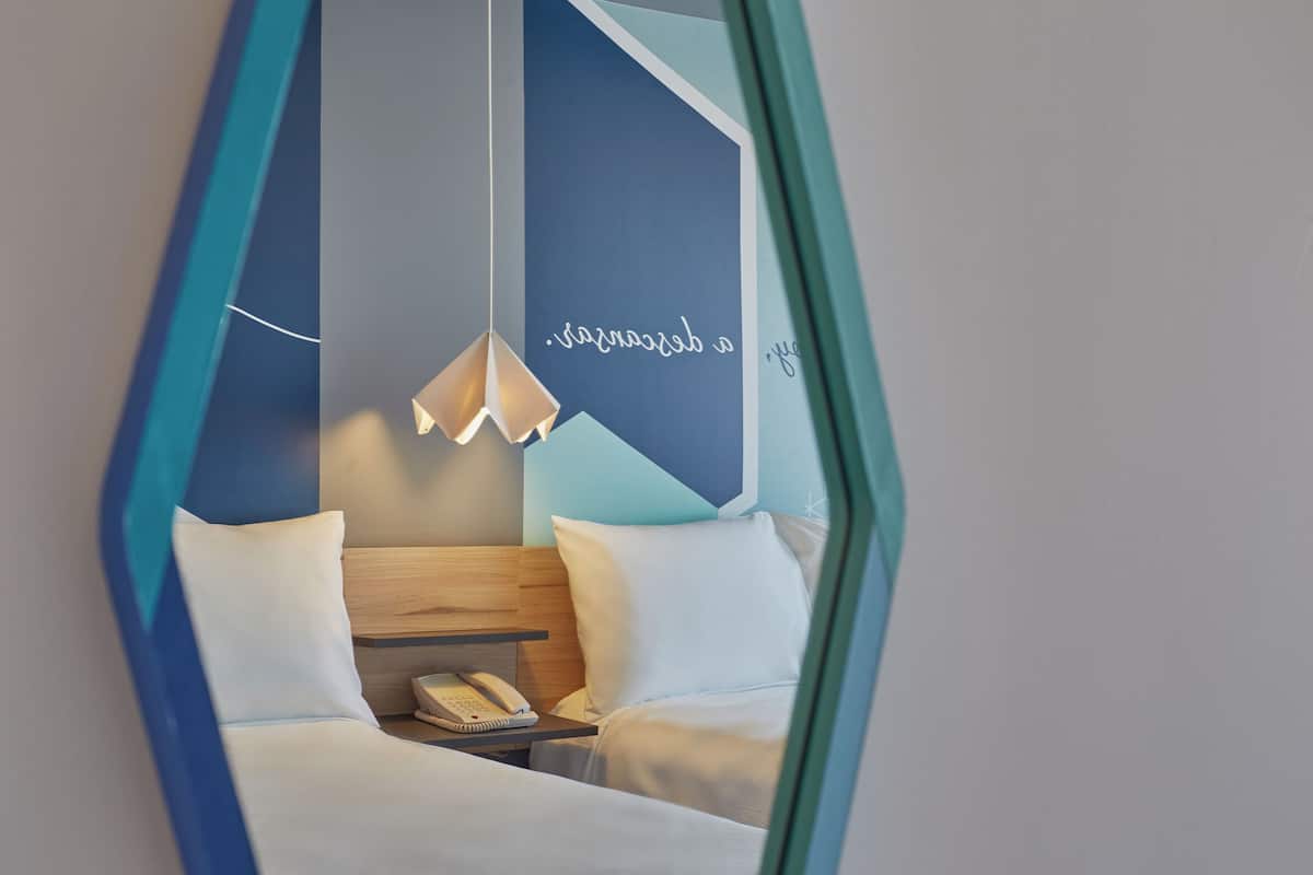 A hotel room with a bed, bedside table, and a hanging light fixture.