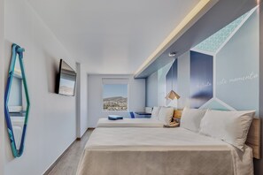 Moderni hotellihuone, jossa on suuri sänky, työpöytä, tuoli, peili ja näkymä kaupunkiin.
