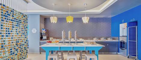 Una cocina moderna con una paleta de colores azul y blanco, una isla central con taburetes y un salpicadero con diseño.