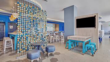 A modern children's play area with hexagonal flooring, blue and white furniture, and a colorful wall decoration.