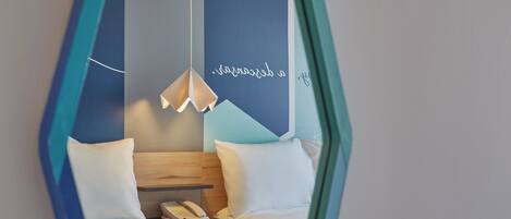 A modern hotel room with a bed, bedside table, and a hanging light fixture.