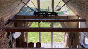 Una habitación con techos altos, techo de madera, ventanas amplias y una lámpara colgante.