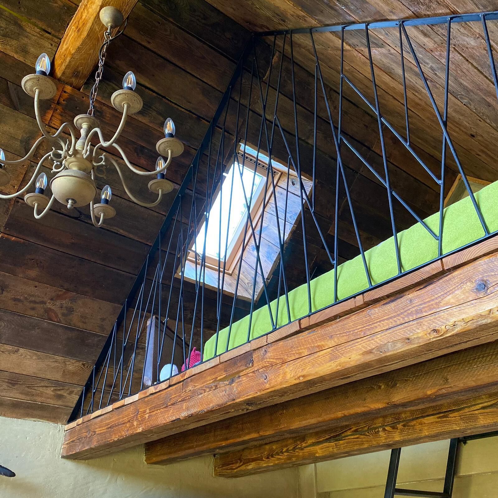A wooden staircase with a metal railing, a chandelier, and a skylight.