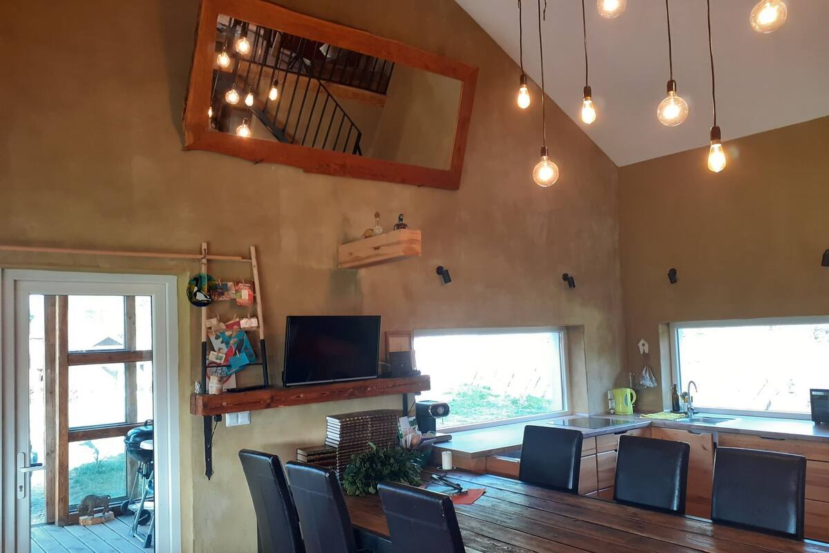 A dining area with a wooden table and chairs, a television on a shelf, and a large mirror on the wall.