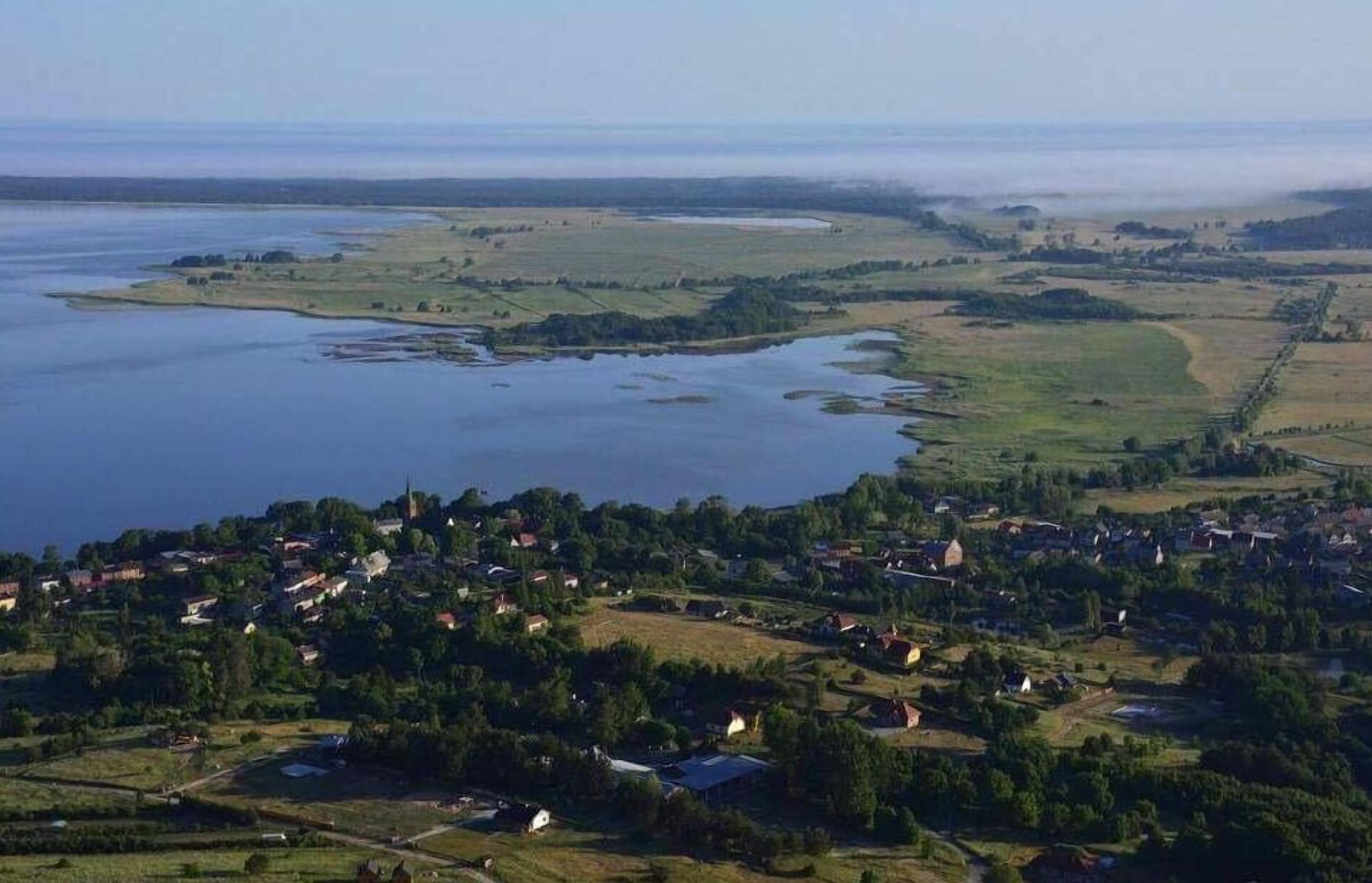Un pueblo costero con una mezcla de edificios residenciales y comerciales, una extensa masa de agua y un paisaje montañoso.