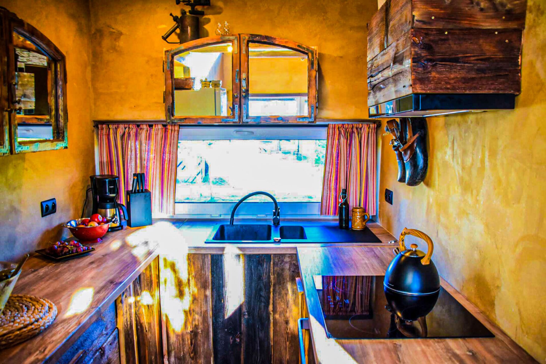 A compact kitchen with a wooden countertop, a sink, and a kettle.