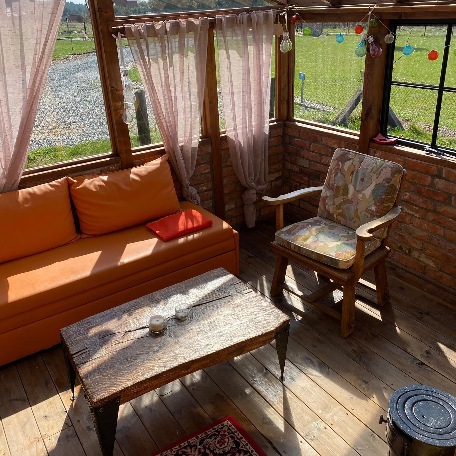 Una habitación acogedora con suelo de madera, pared de ladrillo, un banco de madera y un sofá con cojines.