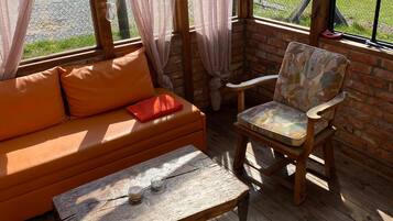 Una habitación acogedora con suelo de madera, pared de ladrillo, un banco de madera y un sofá con cojines.