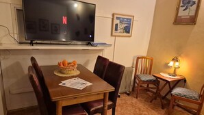 A dining area with a TV, a table with chairs, a basket of bread, and a lamp. - Ocean View Apartment Casa Las Playitas – Terrace – 1 Minute to the Beach (Las Playitas)