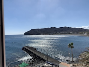 Eine Küstenansicht mit einem Steg, Booten und einem Berg im Hintergrund.