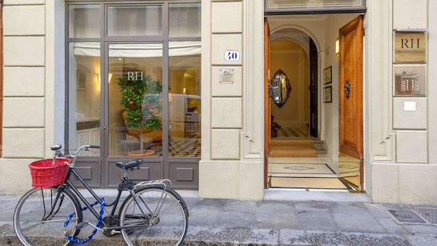 L’entrée d’un hôtel, avec un vélo garé à l’extérieur, un panier rouge fixé au vélo et une pancarte indiquant le numéro de chambre : 70.