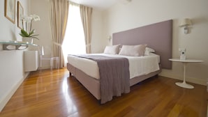 Une chambre à coucher avec un lit, une table de chevet, une lampe et une fenêtre avec des rideaux.