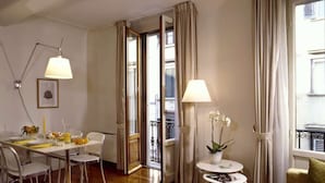 Un salon moderne avec un coin repas, doté d’un parquet, d’un canapé, d’une table basse et d’une lampe.