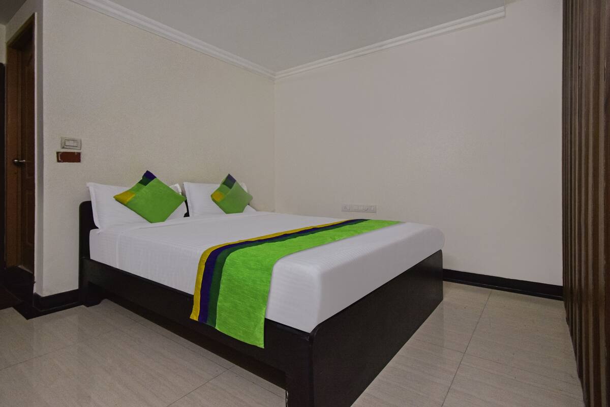 Ein Hotelzimmer mit Bett, Nachttisch, Steckdose und Tür.
