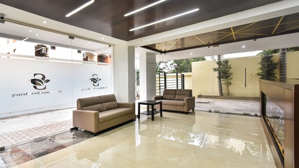 Un área de recepción moderna con un sofá, sillones y un separador de vidrio que muestra logotipos.