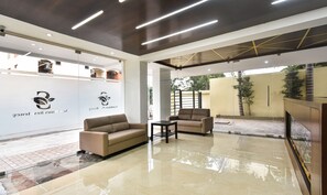 Een moderne receptie met een bank, fauteuils en een glazen wand met logo's.