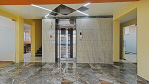 Un vestíbulo con suelo de mármol, un ascensor de vidrio y una puerta con el número 4.