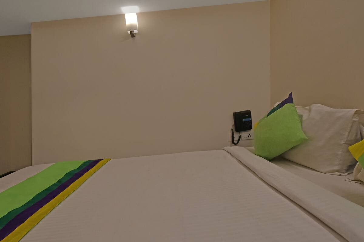 Ein Hotelzimmer mit Bett, Wandtelefon und Nachttisch.