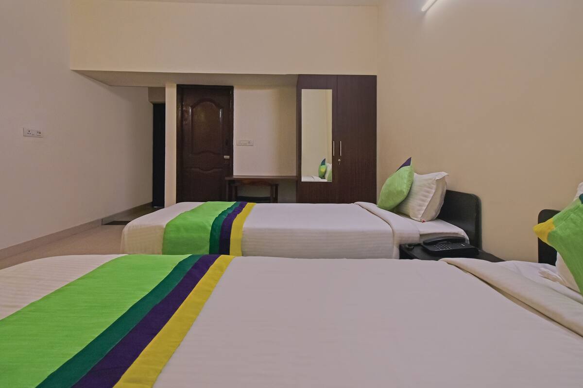 Ein Hotelzimmer mit zwei Betten, einem Spiegel, einem Schreibtisch und einem Telefon.