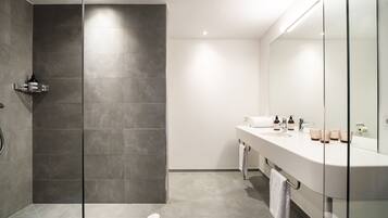 A modern bathroom with a glass shower enclosure, a white sink with a mirror, and a towel rack.