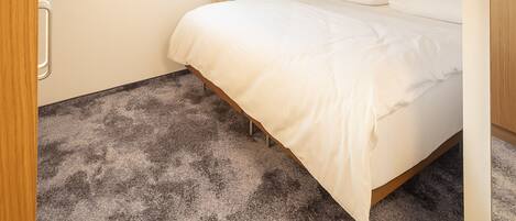 A hotel room with a large bed, a window with curtains, a ceiling light, and a carpeted floor.