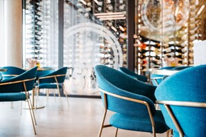 A modern interior with teal chairs and a glass display wall. - FIRMAMENT Hotel (Rankweil)