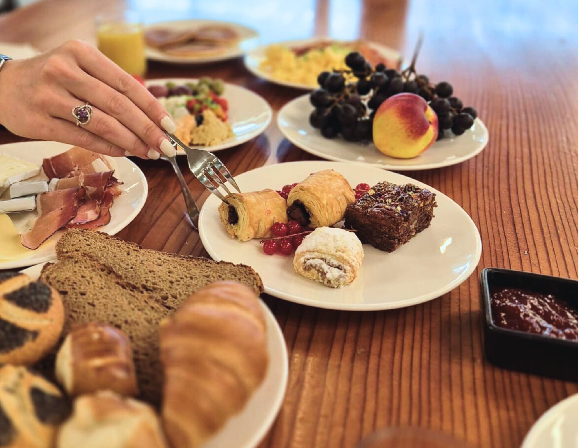 A breakfast table with croissants, pastries, and a variety of fruits.