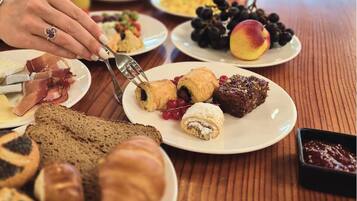 A breakfast table with croissants, pastries, and a variety of fruits.